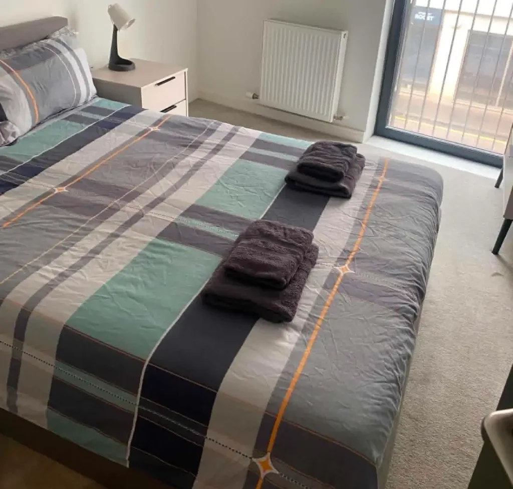 A frshly made bed with towels laid neatly on top